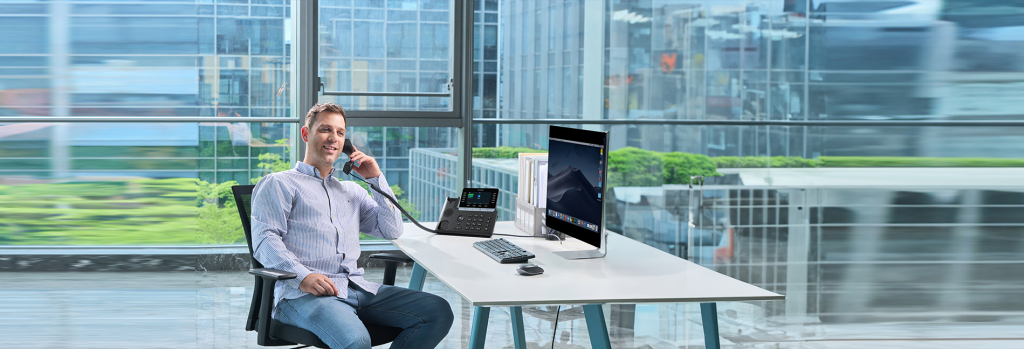 Professional taking a call on a business desk phone in an office overlooking the city